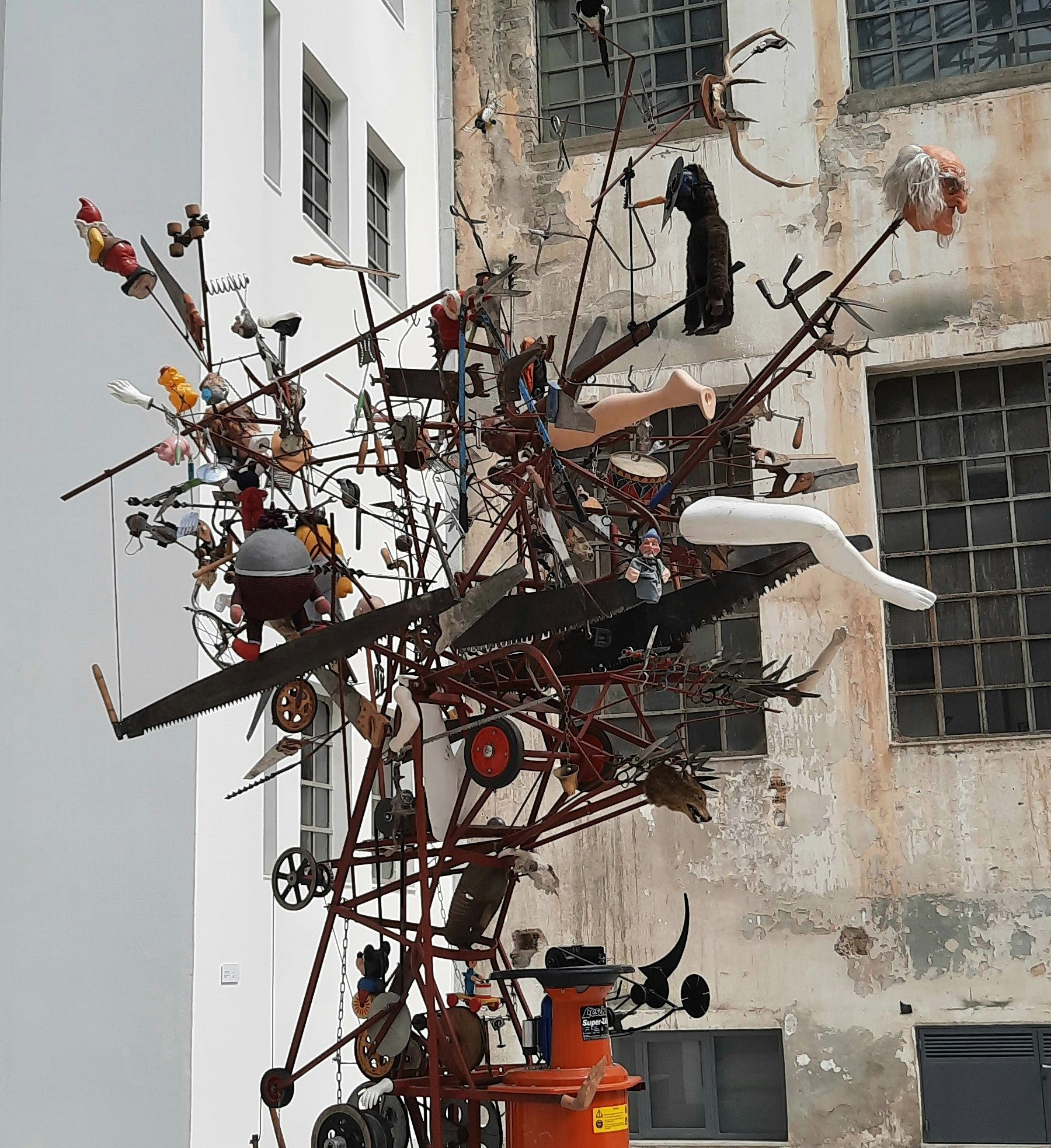 An intricate outdoor sculpture made of tools, figures, and mechanical parts.